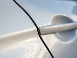 China vehicle recall, macro of a flush door handle seam on wet pearl white car paint