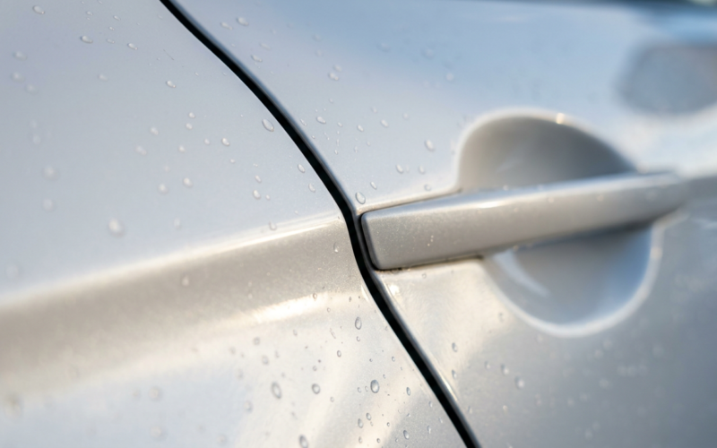China vehicle recall, macro of a flush door handle seam on wet pearl white car paint