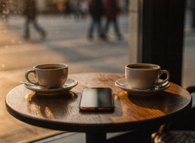 Two coffee cups at a cafe window with a phone face down as people step away from dating apps