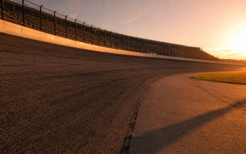 Empty high banked oval speedway photographed from trackside at golden hour