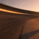Empty high banked oval speedway photographed from trackside at golden hour