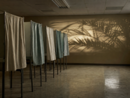 Florida primary governor race shown by empty voting booths in a polling place at night with palm shadows on the wall