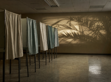 Florida primary governor race shown by empty voting booths in a polling place at night with palm shadows on the wall