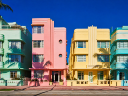 Row of pastel art deco facades in mint green flamingo pink and butter yellow under blazing midday sun