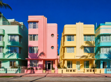 Row of pastel art deco facades in mint green flamingo pink and butter yellow under blazing midday sun