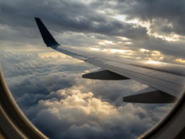 Turbulence nowcast illustrated by an airliner wing seen through a cabin window above a churning layer of storm cloud tops