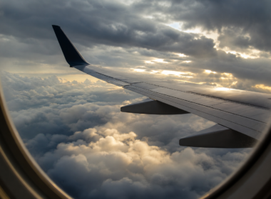 Turbulence nowcast illustrated by an airliner wing seen through a cabin window above a churning layer of storm cloud tops