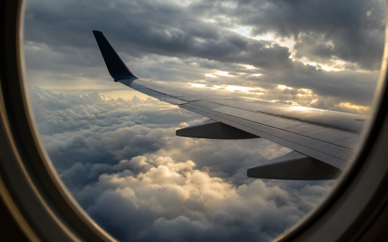 Turbulence nowcast illustrated by an airliner wing seen through a cabin window above a churning layer of storm cloud tops