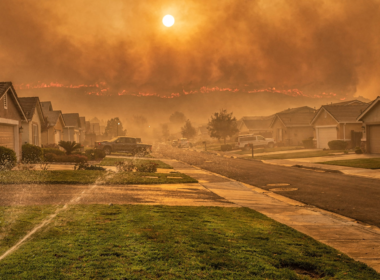 Hawk Fire Reno concept, suburban street under an orange smoke sky with a sprinkler running