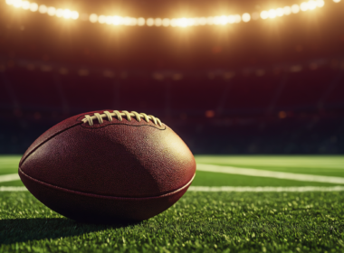 A football stadium at dusk with a rising spotlight, symbolizing high expectations for a young quarterback