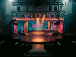 Empty late night television studio seen from the back of the audience risers under teal and magenta stage light