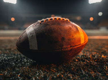 An empty football field under stadium lights, representing a team built to contend