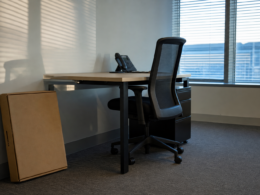 Quits rate decline illustrated by an empty office desk with the chair pushed in and an unopened flat moving box on the floor