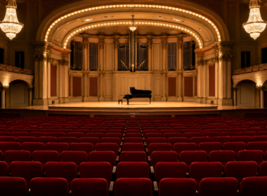A grand performing arts hall exterior with dramatic evening light, evoking a cultural institution in dispute