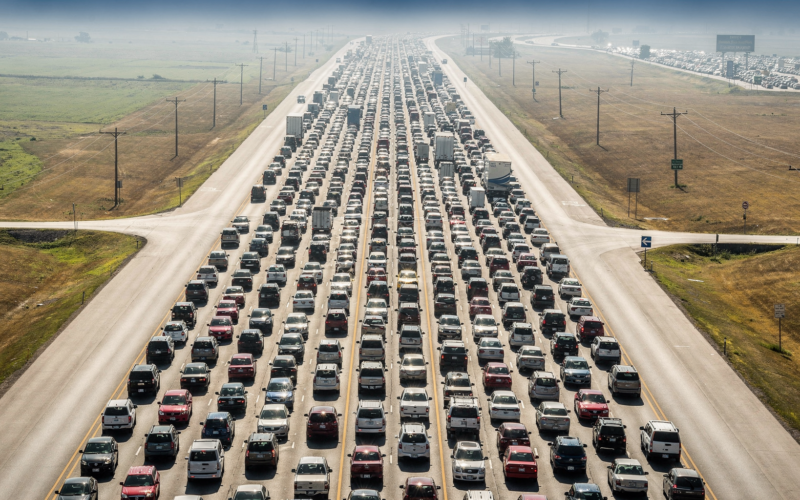 Labor Day travel 2026 traffic packed across an interstate lane by lane in midday heat haze