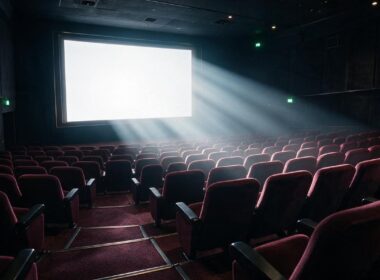 A dark cinema hall with a glowing blank screen and dramatic beams of light