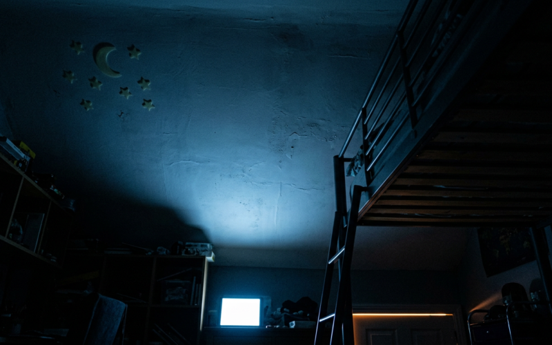 Meta child addiction trial, dark bedroom ceiling lit cold blue from an unseen screen below