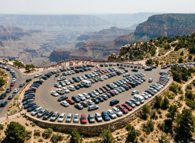 National park crowds shown as tightly packed rows of parked cars at a canyon scenic overlook viewed from above