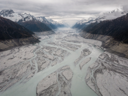 Aerial view of a Himalayan valley filled with grey glacial silt and floodwater