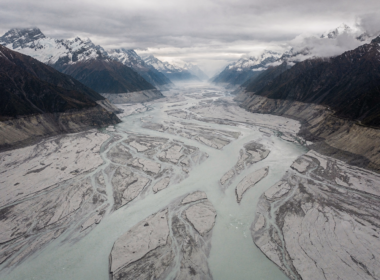 Aerial view of a Himalayan valley filled with grey glacial silt and floodwater