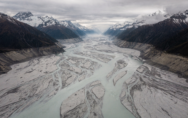 Aerial view of a Himalayan valley filled with grey glacial silt and floodwater