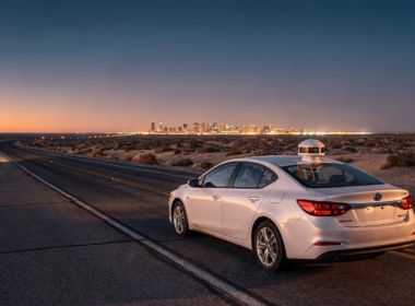 Nevada robotaxi permits concept, desert highway at dusk with a sensor equipped sedan