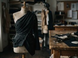 Dark draped fabric pinned on a dress form in a design studio evoking Rachel Scott Proenza Schouler tailoring