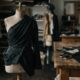 Dark draped fabric pinned on a dress form in a design studio evoking Rachel Scott Proenza Schouler tailoring