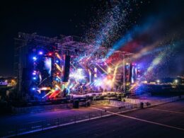 SB19 and BINI concept: a festival stage lit with colorful spotlights and confetti at night