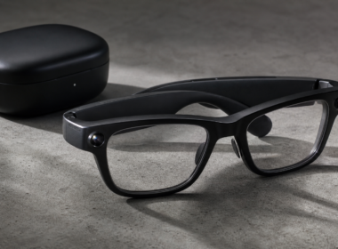 Smart glasses with a small camera lens and a speaker arm resting on a concrete surface