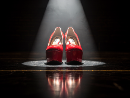 Low angle view of scarlet patent platform heels lit by a hard theatrical spotlight