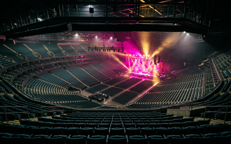 Live Nation settlement concept, empty arena from the top row with the stage lit magenta and gold
