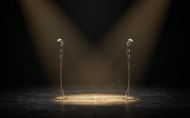 Verzuz Donell Jones vs Joe, two vintage microphones facing each other on a dark stage