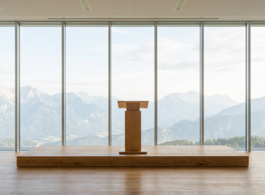 Empty wooden lectern on a stage before a full height window wall looking out at mountains