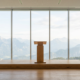Empty wooden lectern on a stage before a full height window wall looking out at mountains