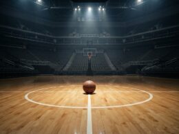 Empty indoor basketball arena with a single ball at center court under overhead spotlights, illustrating the 2026 WNBA trade deadline